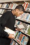 Young man choosing books in library