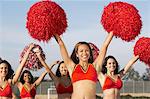 Cheerleaders with pom poms raised