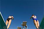 Two female swimmers standing on diving board