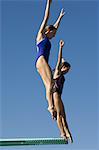 Two women jumping on diving boards