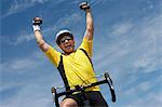 Cyclist riding bicycle and cheering, portrait, low angle view