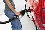 Young woman filling up car with gas, mid section