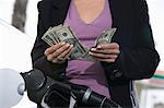 Young woman counting money at service station