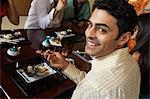 Young people eating sushi with chopsticks in restaurant, elevated view