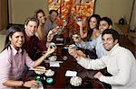 Young people toasting with saki cups in Japanese restaurant