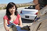 Police officer ticketing  young woman driver on desert highway