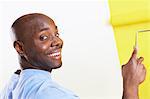 Man painting interior wall yellow, portrait