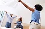Couple holding bed sheet over son (3-6)