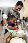 Fils (3-6) aidant les plats de lavage père