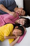 Mother, father and daughter lying down on bed with eyes closed