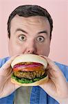 Overweight mid-adult man eating hamburger