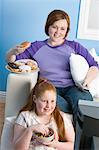 Übergewichtige Mädchen und Mutter vor dem Fernseher, Essen