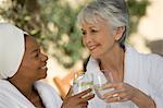 Two women in bathrobes, toasting drinks