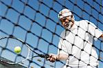 Senior homme frappant à coup de droit près de filet de tennis tennis ball