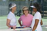 Drei Frauen reden am Tennisplatz