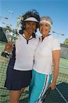 Two female tennis players with award cup