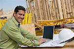 Construction worker using laptop, portrait