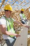Deux travailleurs de la construction mesure planche de bois