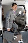 Asian businessman getting off airplane.