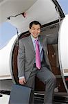Portrait of Asian businessman getting off private airplane.