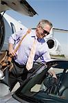 Senior businessman getting of airplane and getting in car.