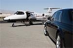 Limousine and private jet on landing strip.