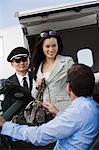Mid-adult businesswoman getting out of airplane, two men assisting.