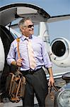 Senior businessman in front of private jet.