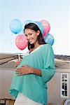 Schwangere Frau hält Luftballons, außerhalb