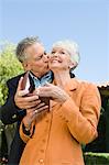 Senior man kissing wife on cheek and giving present