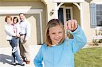 Girl (7-9) holding keys, rest of family in background