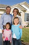 Portrait of family with two children (6-9) in front of new house