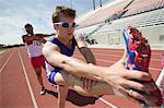 Male sprinters stretching on track