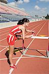 Female athlete stretching on hurdle