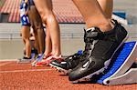 Group of female track athletes on starting blocks, close-up view