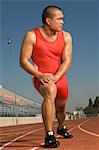 Male athlete stretching on track