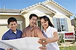 Family looking at plans in front of new home