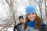 Couple standing outdoors, holding skis in snow