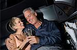 Middle-aged couple sitting on back seat of limousine and drinking champagne