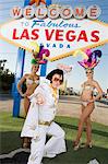 Female dancers and Elvis impersonator posing in front of Las Vegas welcome sign, Nevada, USA