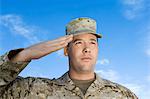 Soldier saluting against sky, (close-up)