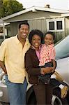 Couple with young boy standing by car in front of bungalow