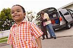 Young boy standing in front of parents by car