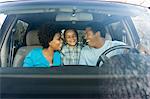 Couple smiling at young son in car, view through windscreen
