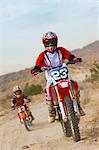 Mother and son (5-6) on motocross bikes in desert
