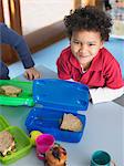 Boy sitting at table with open lunch box, elevated view, portrait