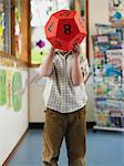 Boy holding oversize twelve-sided dice in classroom