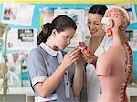 teacher with student examining part of anatomical model in classroom