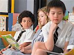 Elementary students reading books, sitting in classroom