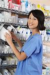 Female nurse standing at shelf with medicines, portrait